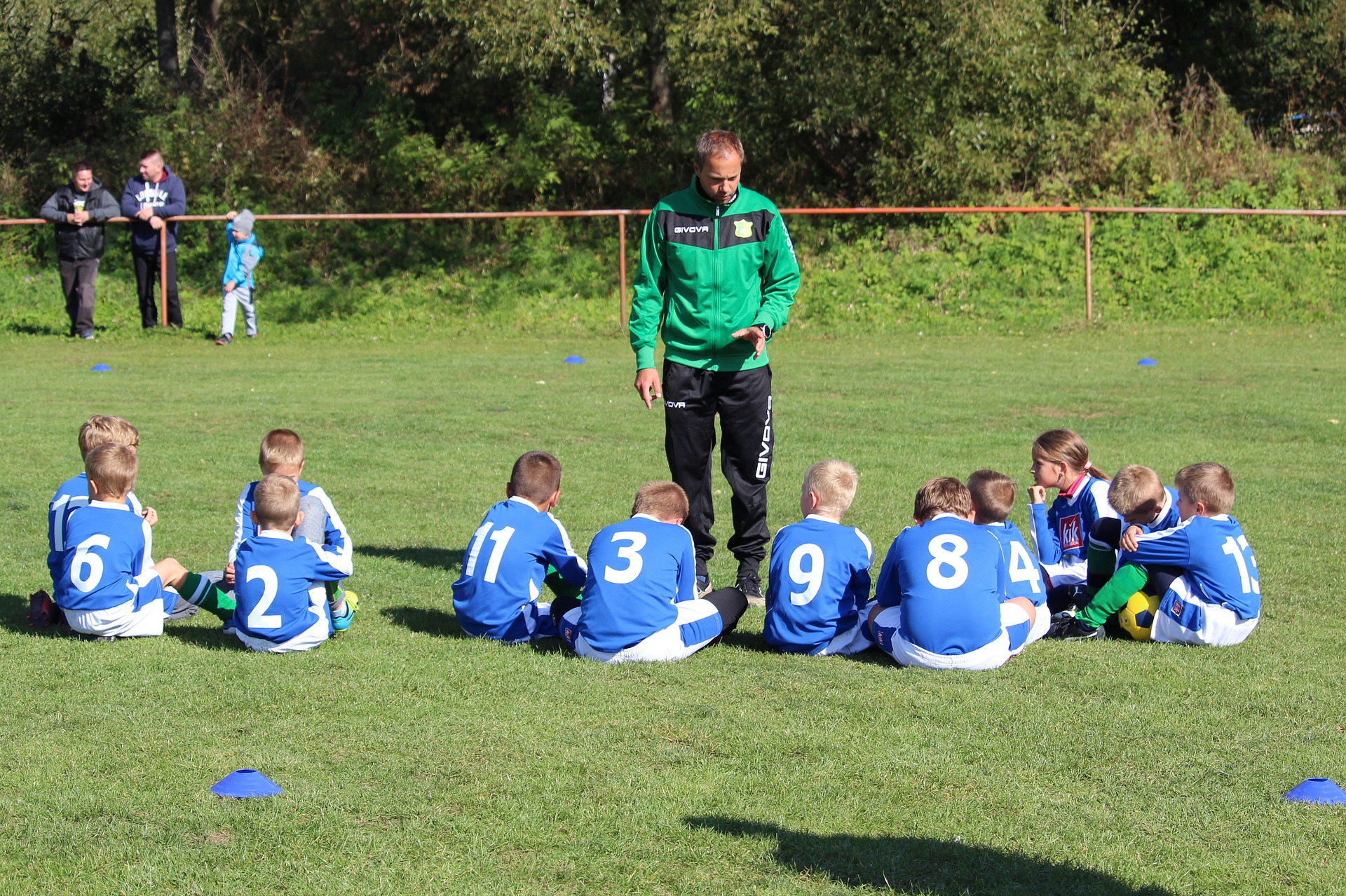 Een coach coacht een groep jonge voetballers